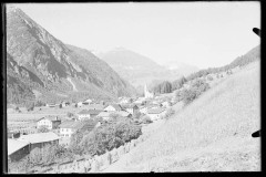 Ortszentrum mit Kirche umgeben von felsigen Bergen