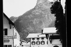 Ortschaft mit Geschäft umgeben hohen, bewaldeten Bergen.