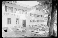 Gasthof Alpenrose mit leeren. eingedeckten Tischen und offenen Sonnenschirmen.