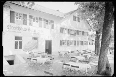 Gasthof Alpenrose mit leeren. eingedeckten Tischen und offenen Sonnenschirmen.