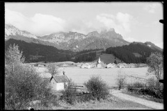 Ortschaft Grän mit Kirche und Ortszentrum, umgeben von leicht verschneiten Bergen und Wald