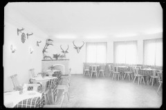 Stube/ Speisezimmer Café - Hubertus Bach von innen, mit Tiergeweihen an den Wänden und mit Blumen geschmückten Tischen