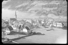 Ortschaft mit Zentrum, Wohnhäusern und Kirche von Wald und Bergen umgeben