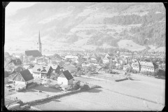 Ortschaft mit Zentrum, Wohnhäusern und Kirche von Wald und Bergen umgeben