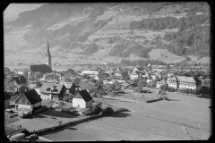 Ortschaft mit Zentrum, Wohnhäusern und Kirche von Wald und Bergen umgeben