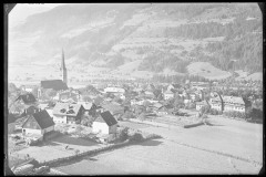 Ortschaft mit Zentrum, Wohnhäusern und Kirche von Wald und Bergen umgeben