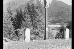 Bildstock mit Abbild von Jesu am Kreuze an einem Feldweg in Nesselwängle, dahinter die Berge