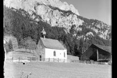 Kleine Kapelle beim Nesselwängle, dahinter eine Scheune und verschneite Berge