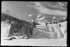 Dick verschneite Holzhütten, Fuß/- Skispuren, Menschen in einer Schneelandschaft