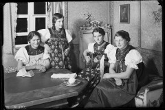 Gruppe von Erwachsenen (männlich u. weiblich) gekleidet in der Walser Volkstracht, tanzend und am musizieren in der Stube