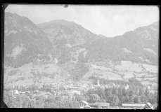 Ortschaft mit Zentrum, Wohnhäusern und Kirche von Wald und Bergen umgeben