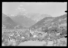 Ortszentrum mit Kirche und Wohnhäusern, von Bergen umgeben