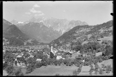 Ortszentrum mit Kirche und Wohnhäusern, von Bergen umgeben
