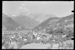 Ortszentrum mit Kirche und Wohnhäusern, von Bergen umgeben