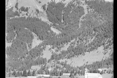 Ortszentrum Grän mit Kirche und Wohnhäusern, umgeben von Bergen und Wald