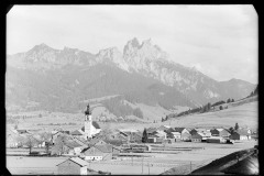 Ortszentrum Tannheim mit Kirche und Wohnhäusern, umgeben von Bergen und Wald
