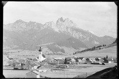 Ortszentrum Tannheim mit Kirche und Wohnhäusern, umgeben von Bergen und Wald