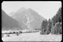 Blick auf eine Ortschaft mit Kirche, dahinter eine Bergkulisse