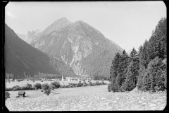 Blick auf eine Ortschaft mit Kirche, dahinter eine Bergkulisse