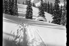 Dick verschneite Schneelandschaft, mit Fuß/-Skispuren, Wald, Hütten und Berggipfeln