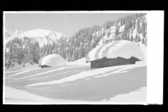 Dick verschneite Schneelandschaft mit Holzhütten und Berggipfeln