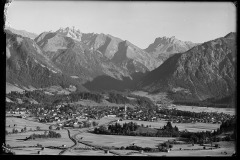 Blick auf das Zentrum mit Kirche in Oberstdorf und dicht bebauten Flächen aus Häusern, eingekesselt von dem Wald und die Berge Oberstdorf