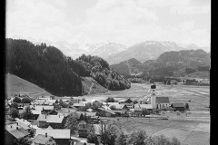 Ortschaft, Zentrum mit Kirche umgeben von Wald und Berggipfeln