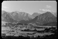 Blick auf das Zentrum mit Kirche in Oberstdorf und dicht bebauten Flächen aus Häusern, eingekesselt von dem Wald und die Berge Oberstdorfs